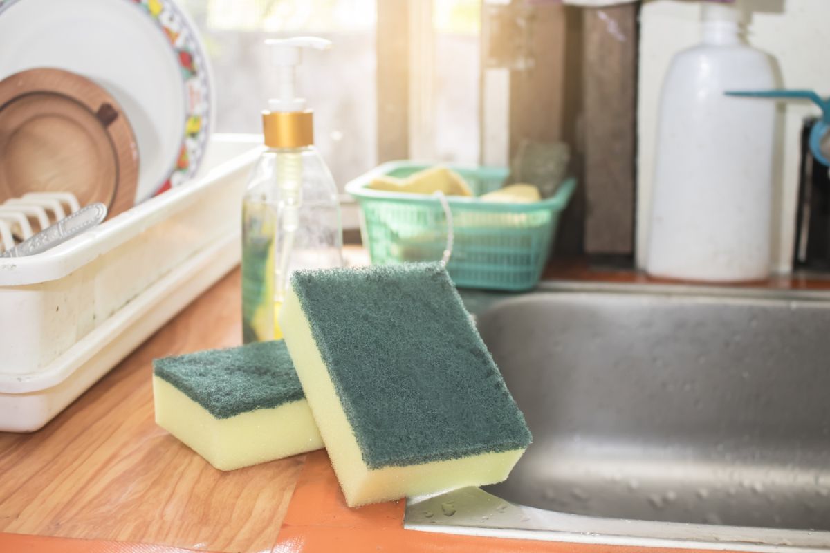 Two kitchen sponges on a kitchen table next to  a washbasin.