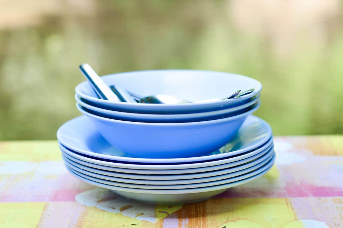 Stack of blue melanine bowls and plates with steel cutlery..