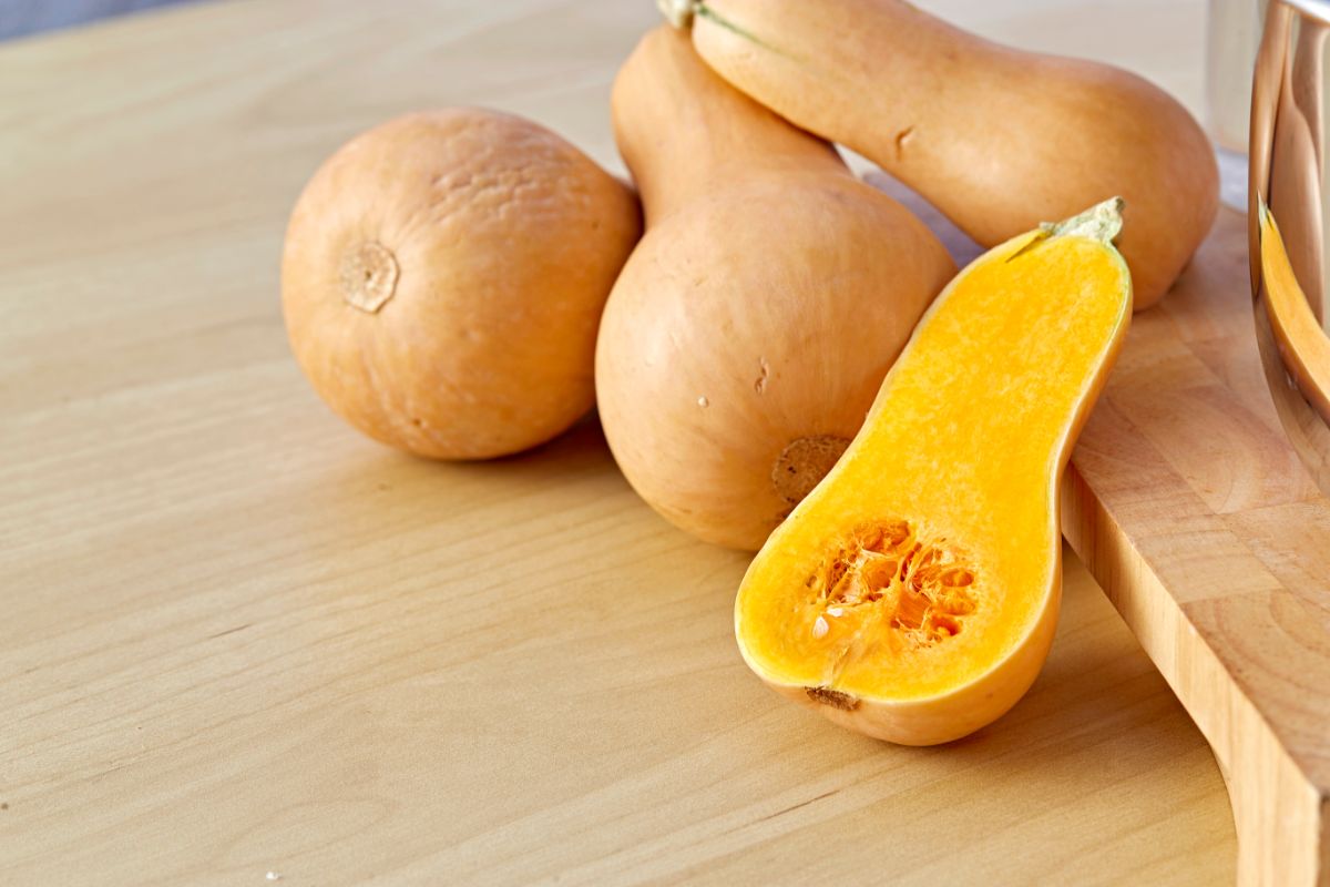 Whole butternut squashes and on half of squash on a table.