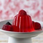 Jelly dessert with ripe strawberries on a cake stand.