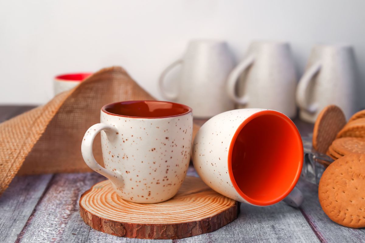 Bunch of white-red creamic mugs on a table. with cookies.