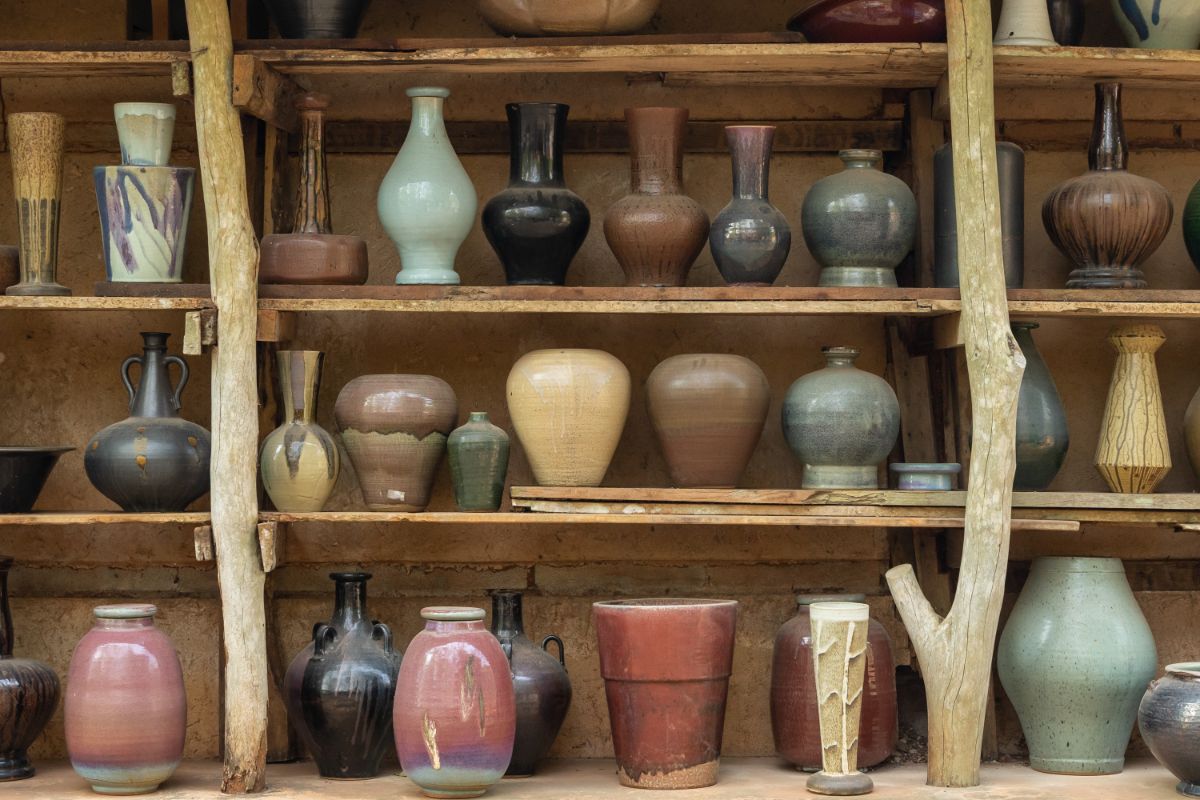 Different varieties of ceramic glazed pottery on  wooden shelves.