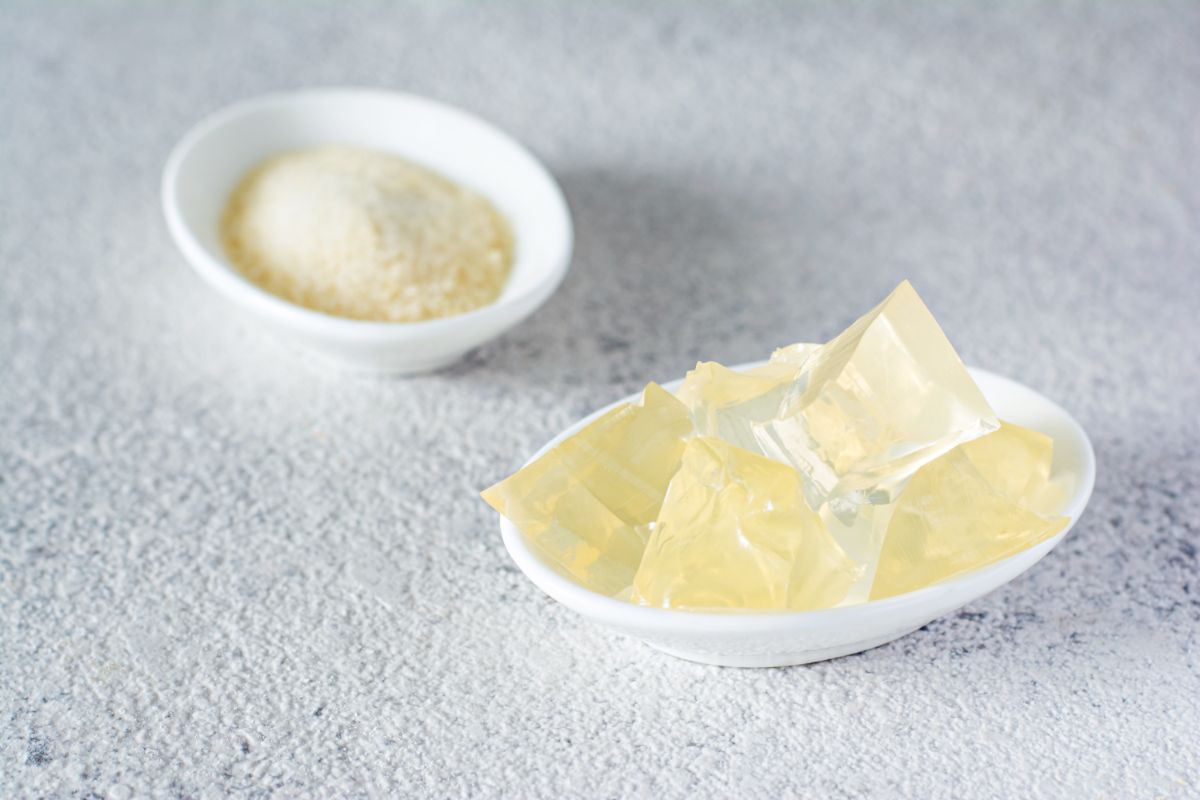 White bowl of a dry gelatine and bowl of gelatine cubes on a table.