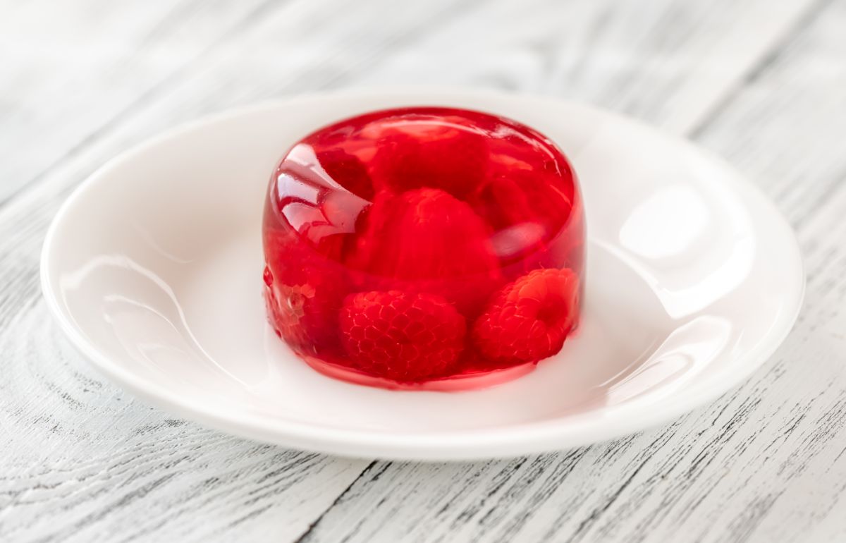 Jello dessert with raspberries on a white plate.