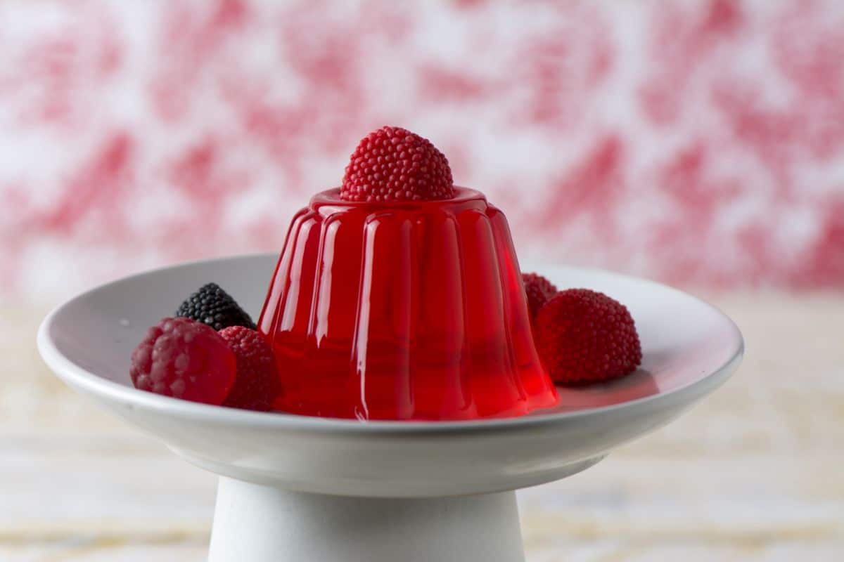 Jelly dessert with ripe raspberries on a cake stand.