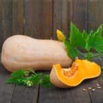 Butternut squash on a wooden table with a herb.