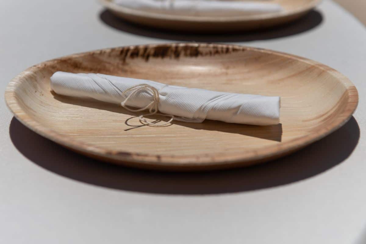 Bamboo plate with wrapped cutlery on a table.