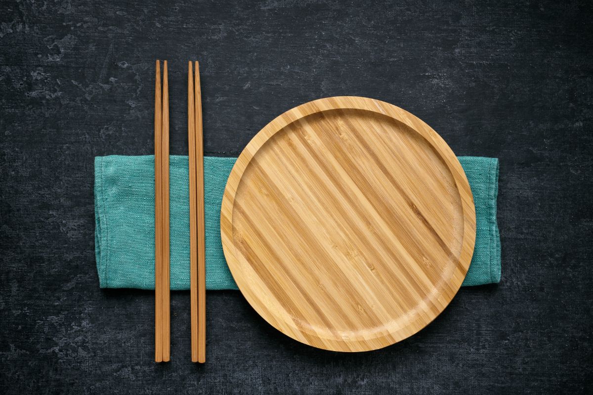Bamboo plate on a green cloth wipe with bamboo sticks on a black table.