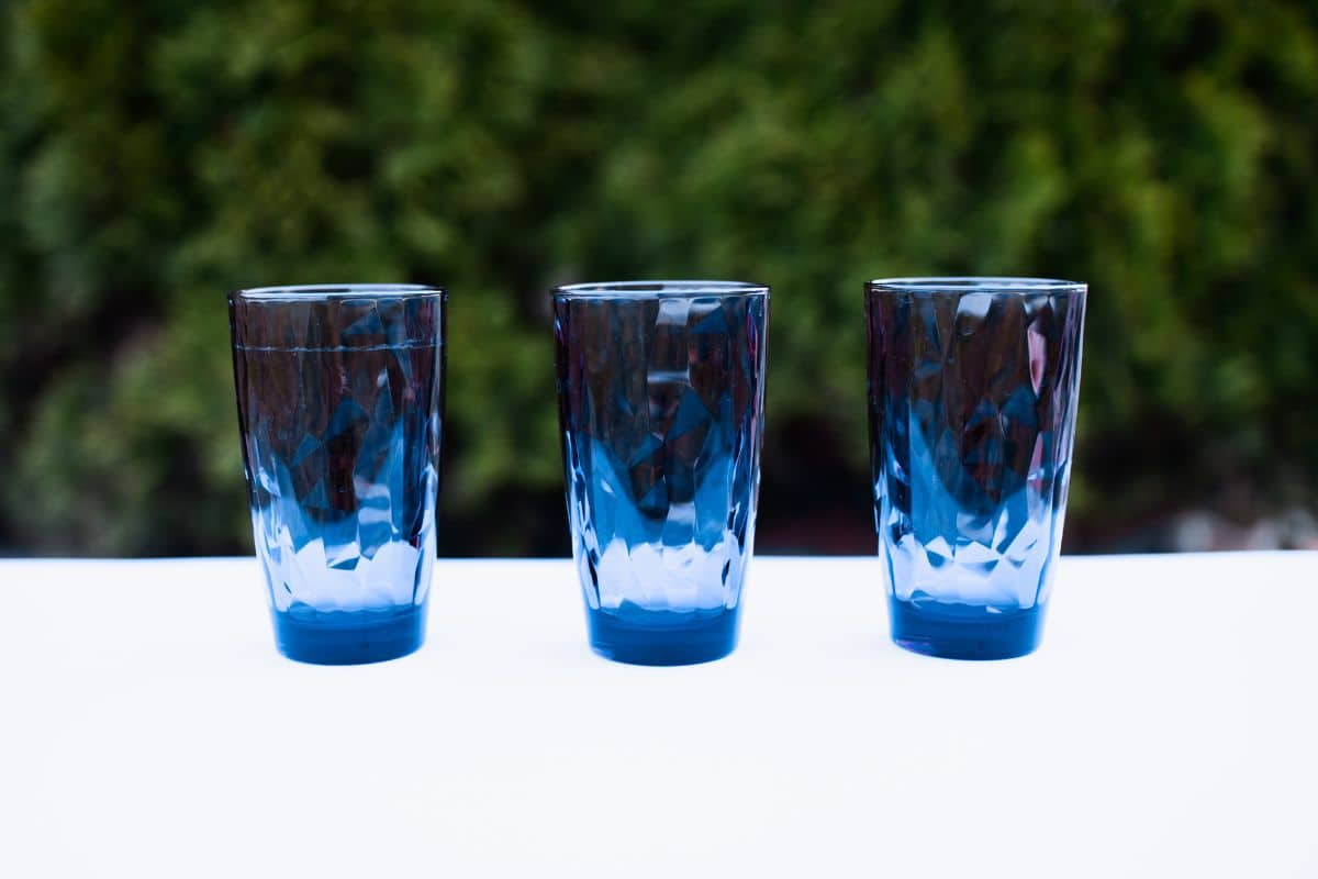 Three blue glass cups on a white table.