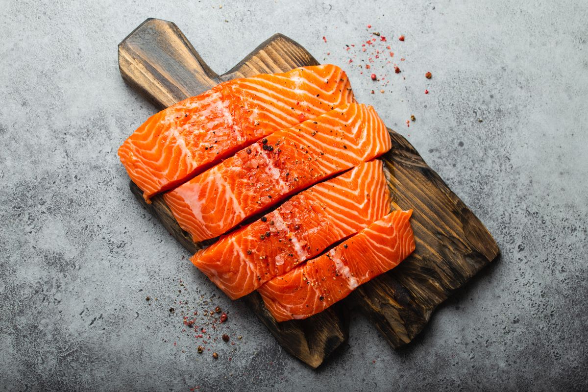 A sliced raw salmon fillet on a wooden cutting board.