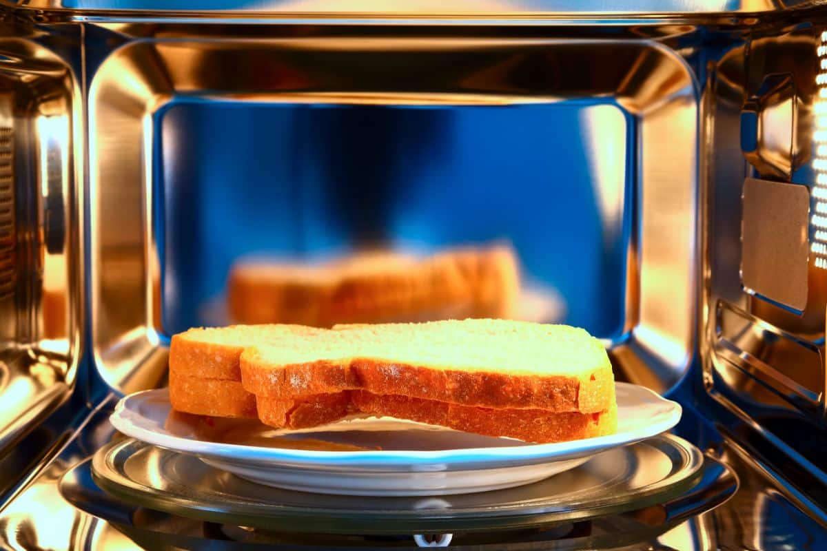 Two slices of bread on a plate in a microwave.