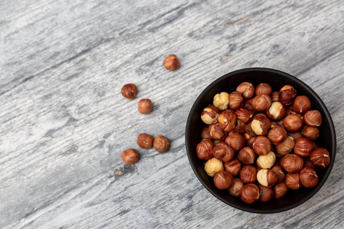 A bowl of roasted nuts on a wooden table.