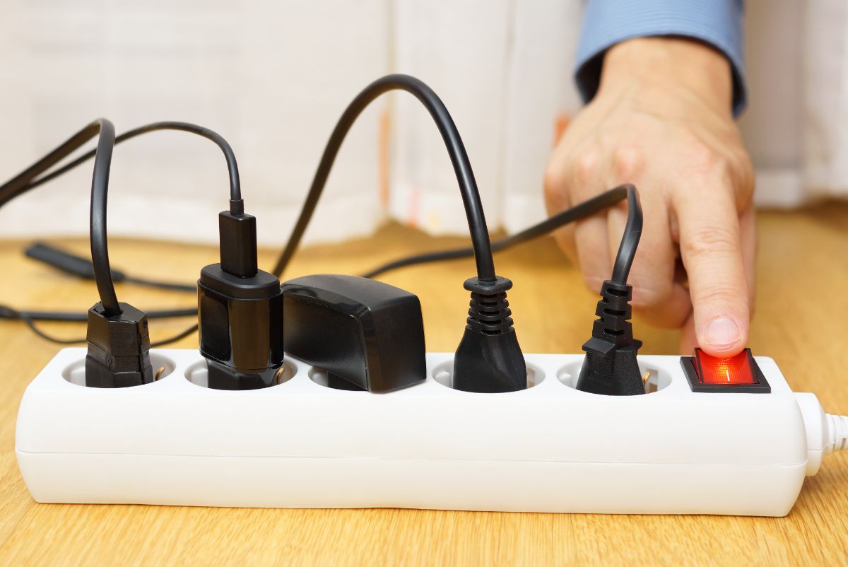 A hand turning off a surge protector.