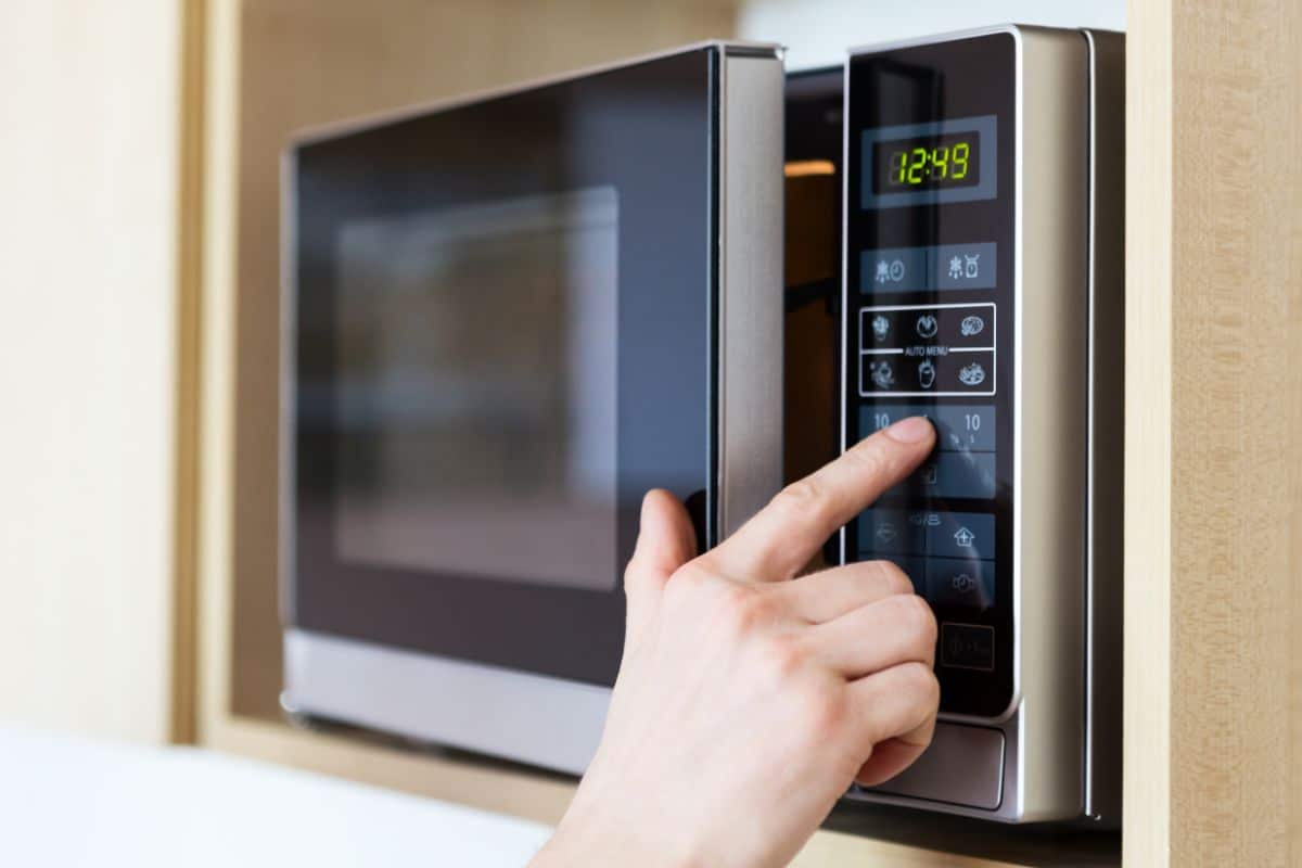 A hand operating and setting a microwave.