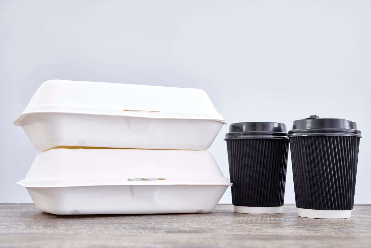 Two Disposable Plastic Containers and two cups on a table.