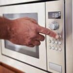 A hand setting up a microwave.
