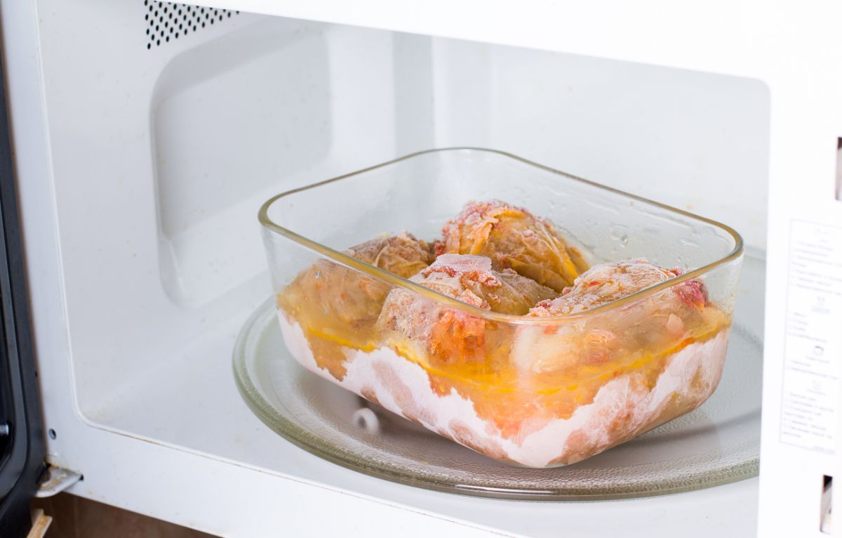 A frozen meal in a glass container in a microwave.