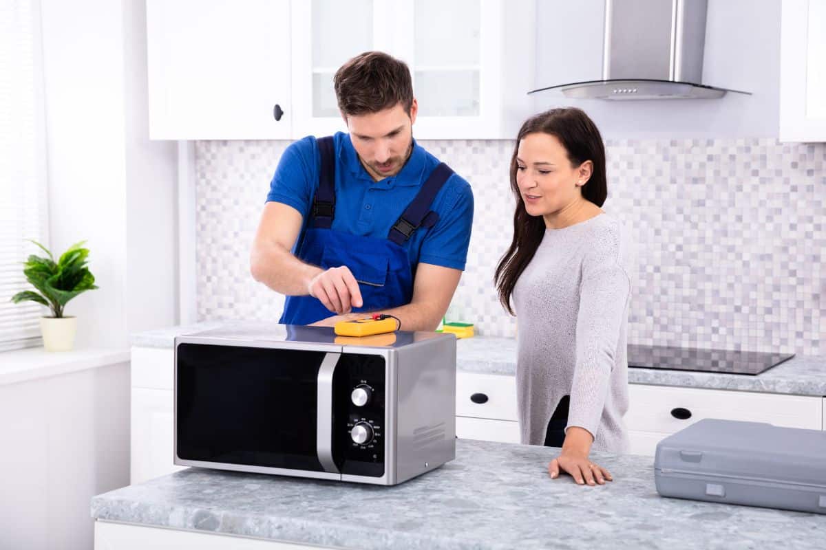 A technician explaining a microwave issue to a young woman.