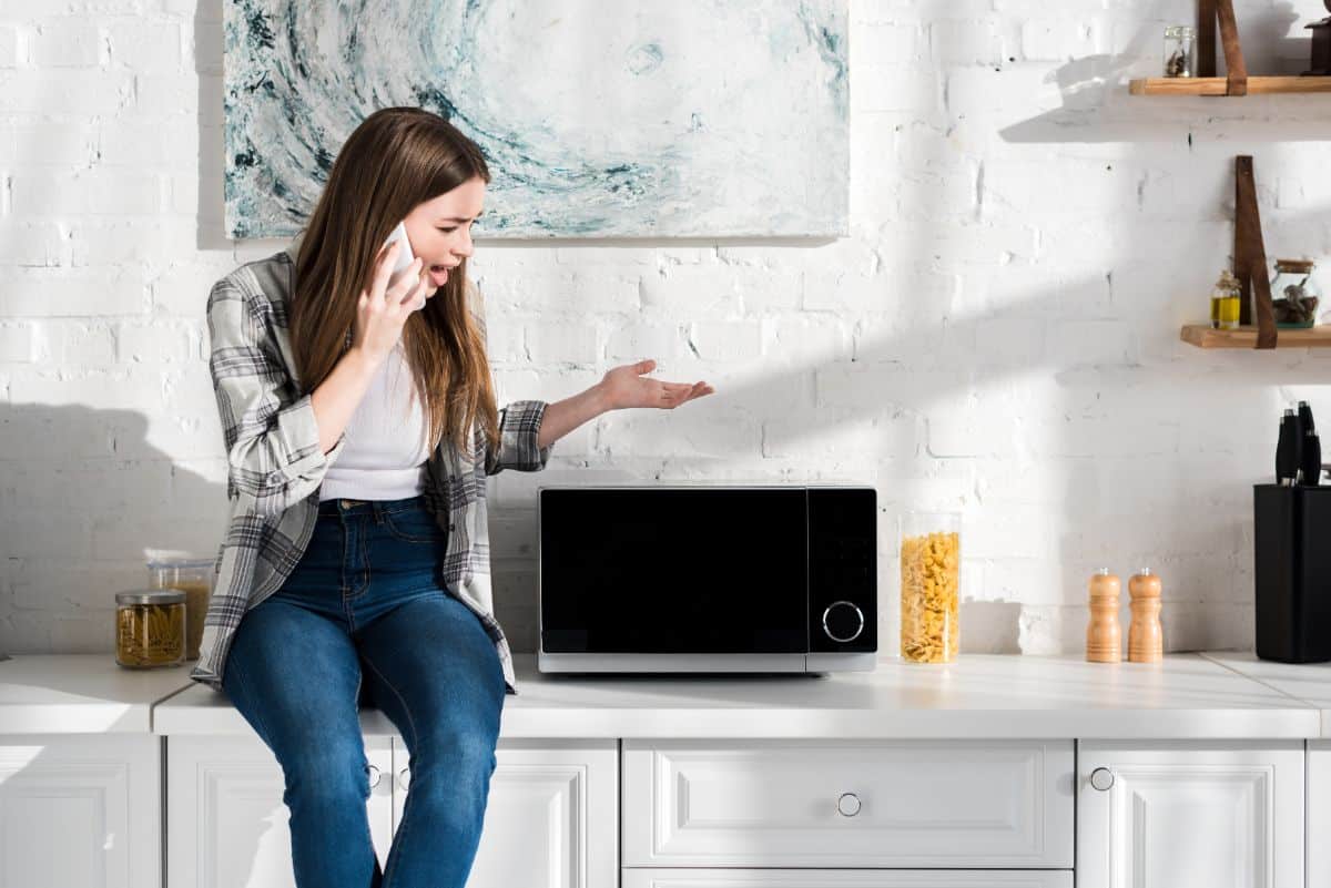 A young woman complaining through a phone call about a microwave malfunction.